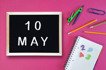 May 10 written in chalk on black board. Calendar date 10th of May on chalkboard on pink blurred...