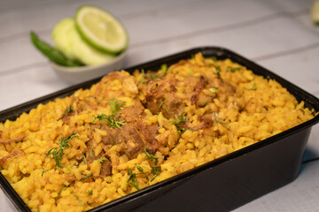 Chicken khichuri biryani rice pulao with cucumber and lemon slice served in dish isolated on wooden...