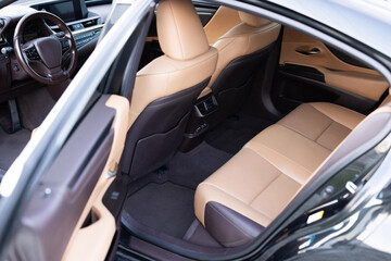 Rear leather passenger seats in modern lux car. Leather car passenger seat. Control unit with electric seat adjustment media system for rear passengers in luxury car. Modern car interior detail