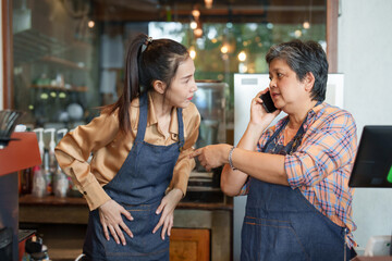 Business owner of small cafe, single mother retired age receiving  pension. Receiving phone calls receiving orders from the other end  coffee machine cute Asian daughter standing there taking orders