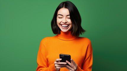 Happy smiling young woman is using her smartphone against green background