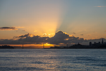 The sun is setting over the water, casting a warm glow over the city skyline