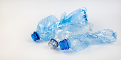 Crumpled used mineral water bottles on a white background. The concept of waste sorting.