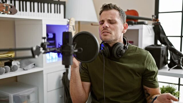 A man sings emotionally into a microphone in a modern music studio, exhibiting passion and focus.