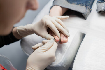 A pedicure master does cleaning and massage, pedicure, to a young beautiful girl with a small foot. Caring for female beauty in a beauty salon during a procedure. Skin of feet and toes close-up