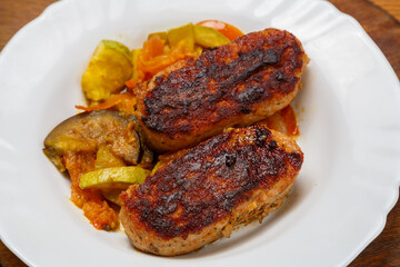 Beef cutlet with fried vegetables on a white plate