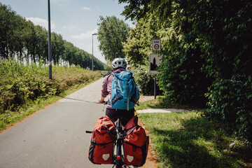 Frau radelt während einer Radreise auf einem Radweg entlang eines Kanals in Flandern, Belgien