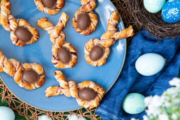 Obraz na płótnie Canvas gedrehter und gefüllter Blätterteig mit Marmelade und einem Ei aus Schokolade zu einem kleinen Hase als Süßspeise zu Ostern im Frühling