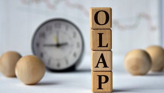 OLAP - acronym on wooden cubes on graph, clock and wooden balls background.