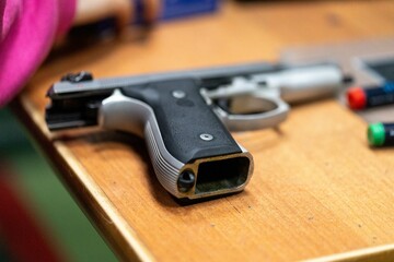 The handle of a gun without a magazine on a table at the shooting range
