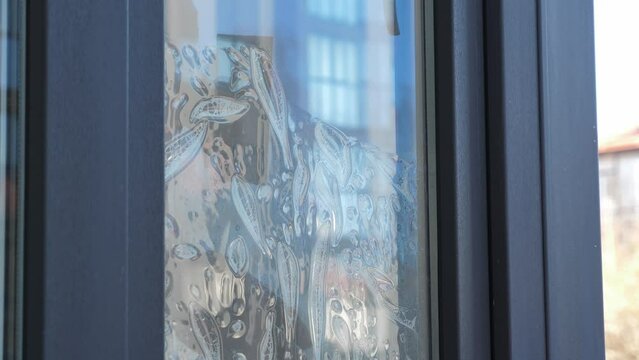 Worker installing and smoothing tint film on window at home. Man tinting windows with squeegee