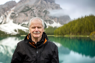 Senior man standing alone at beautiful mountain lake. Symbol for staying active at old age.