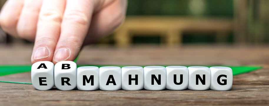 Hand dreht W&uuml;rfel und &auml;ndert das Wort 'Ermahnung'  in 'Abmahnung' .