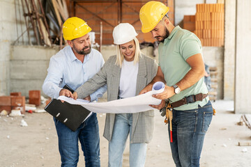 A female architect and construction managers work together on-site, discussing blueprints and coordinating to bring their project to life.
- 758297217