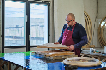 Concentrated and skilled, a man assesses his handiwork in wood. It's a critical step in the art of woodworking.