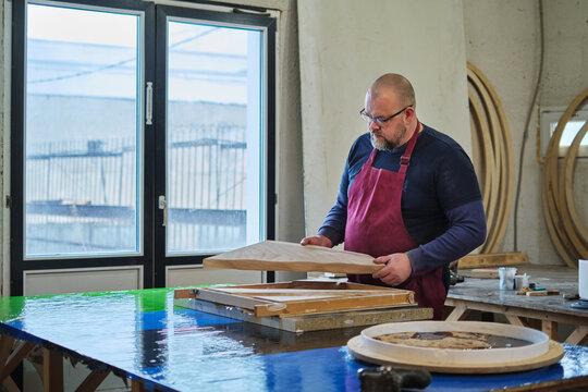 Concentrated and skilled, a man assesses his handiwork in wood. It's a critical step in the art of woodworking. - Powered by Adobe