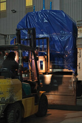 Worker loading cargo onto truck with forklift