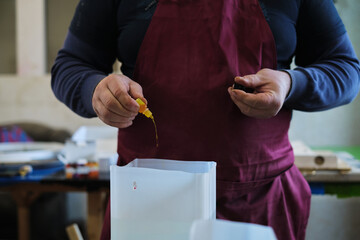 Artisan prepares resin mix, adding color to the clear medium. It's a step that brings vibrancy to the craft piece.