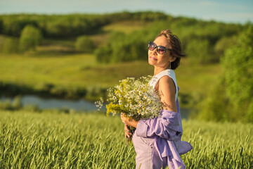 The Asian woman, amidst wheat, holds flowers high; her tranquility a silent narrative on menopause and mental harmony.