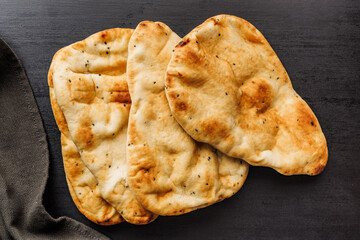 Freshly Baked Naan Bread Resting on a Dark Wooden Table. Top view.