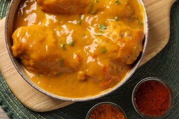 Tasty chicken curry and spices on green place mat, flat lay