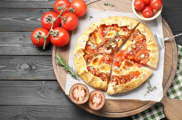 Tasty galette with tomato and cheese (Caprese galette) on black wooden table, top view. Space for text