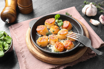Delicious fried scallops in dish served on dark gray textured table, closeup