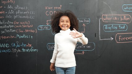 Happy african girl writing blackboard and turnaround to waving at camera while standing at board...