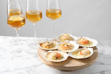 Fried scallops in shells and wine on white marble table
