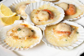 Fried scallops in shells and lemon on plate, closeup