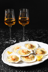 Fried scallops in shells and wine on black textured table