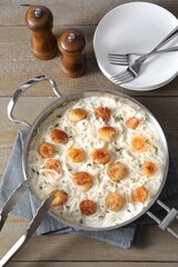 Delicious scallop pasta served on wooden table, flat lay