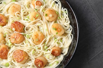 Delicious scallop pasta with green onion on grey table, top view