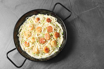 Delicious scallop pasta with green onion on grey table, top view. Space for text