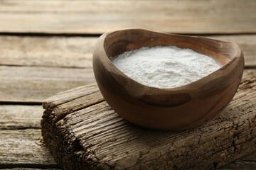 Baking powder in bowl on wooden table, space for text