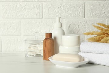 Fototapeta na wymiar Different bath accessories, personal care products and spikelets on white table near brick wall