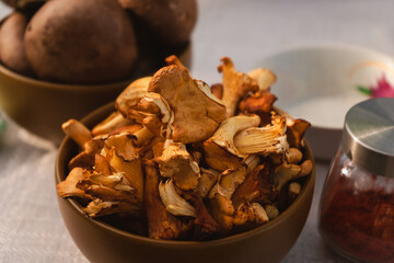 A bowl of dried mushrooms sits next to a jar of red pepper on the table, ready to be used as...