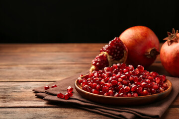 Ripe juicy pomegranates and grains on wooden table. Space for text
