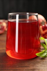 Tasty pomegranate juice in glass on wooden table, closeup