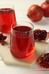 Tasty pomegranate juice in glasses and fresh fruits on white wooden table, closeup