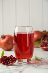 Tasty pomegranate juice in glass and fresh fruits on white marble table