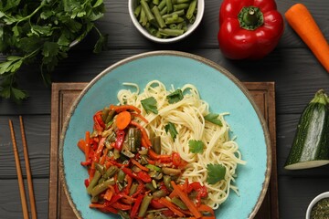 Vegetarian meal. Tasty pasta and fresh vegetables on dark wooden table, flat lay