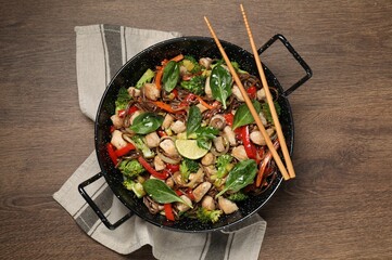 Stir-fry. Tasty noodles with meat in wok and chopsticks on wooden table, top view
