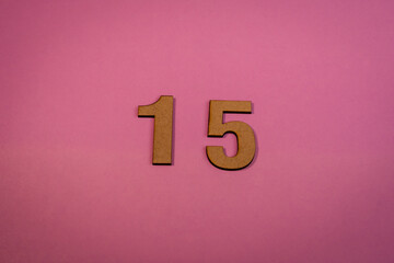 Number 15 in wood on a pink background