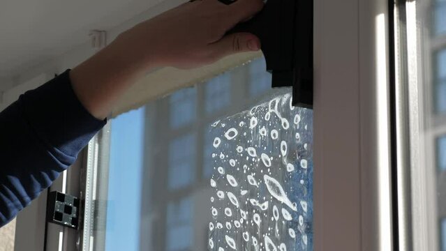 Worker installing and smoothing tint film on window at home. Man tinting windows with squeegee