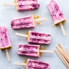 Homemade cherry yogurt popsicles scattered on a light rustic surface.