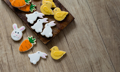 Homemade Easter Holiday cookies in the shape of a cute easter bunnies, carrots and baby chicks on a wooden table texture background with space for text.