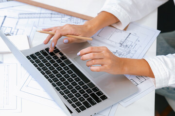Professional beautiful engineer using laptop analysis blueprint with architectural document and...