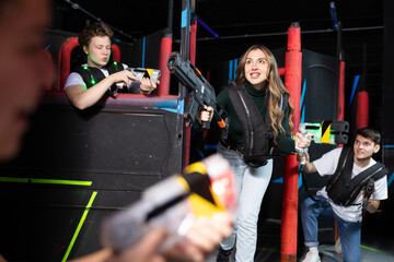 Portrait of excited people playing enthusiastically laser tag game two teams opposite each other in...