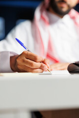A focused businessman of Middle Eastern ethnicity efficiently works at his home office desk, taking...